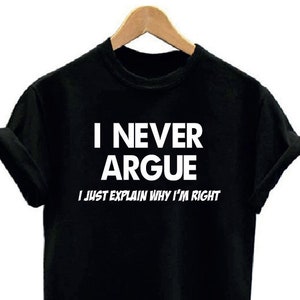 May include: Black t-shirt with the white text "I NEVER ARGUE I JUST EXPLAIN WHY I'M RIGHT". The shirt is hanging on a wooden hanger.