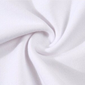 May include: Close-up of white fabric with a soft, textured appearance. The fabric is tightly woven, with visible ridges and a slight sheen, creating a swirling pattern. The image highlights the material's smooth surface and subtle variations in tone.
