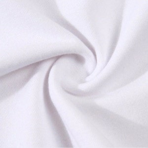 May include: Close-up of white fabric with visible texture and folds. The fabric appears soft and smooth, with a slight sheen. The image highlights the material's texture and the way it drapes.