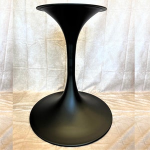 May include: Black tulip table base with a wide, round top and a narrow, curved stem.