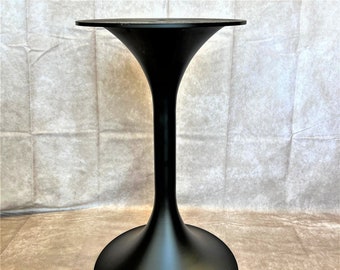 May include: Black metal table base with a wide, round top and a narrow, round bottom. The base is shaped like a trumpet.