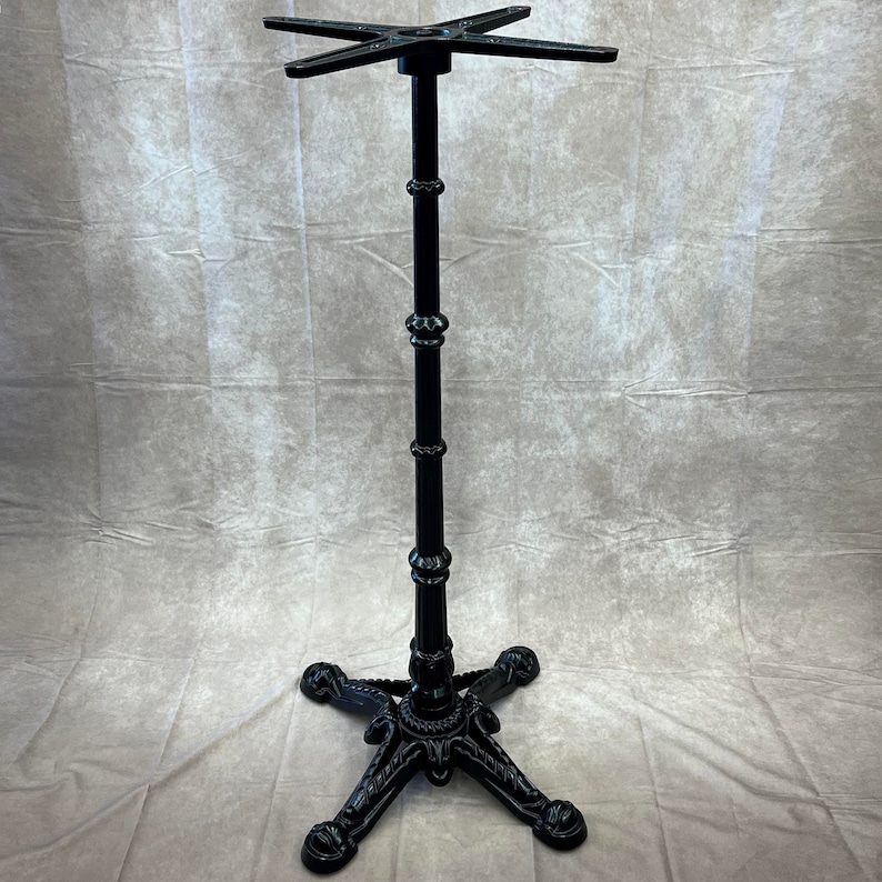 Pu&ograve; includere: Base per tavolo in ghisa nera con un piano a quattro punte e una base decorativa e ornata.