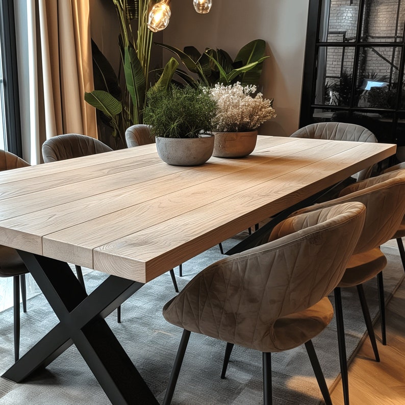 May include: A light wood dining table with a black metal X-shaped base. The table is set with six chairs, four of which are brown velvet with black metal legs. The table is surrounded by a light grey rug.