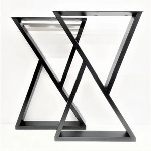 May include: Two black metal table legs with a geometric X-shaped design. The legs are made of thick metal and have a matte finish. The top of each leg has pre-drilled holes for easy attachment to a tabletop. The legs are designed for a modern aesthetic.