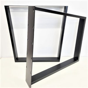 May include: Two black metal table legs with a trapezoidal shape. The legs are made of sturdy metal and have a black powder coat finish.