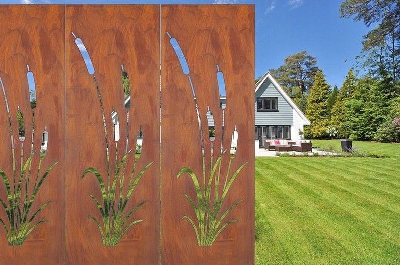 a rust-colored metal screen with a design of reeds or grasses on it, set against a backdrop of a well-maintained lawn and a house surrounded by trees.