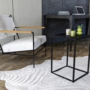 a modern living room with a white cowhide rug, a black metal side table, and a white leather chair with wooden armrests.