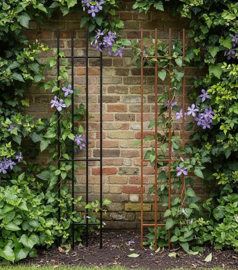 A black metal trellis with purple flowers growing on it, set against a brick wall with greenery.