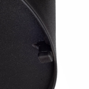May include: Close-up of a black, textured surface with a rounded edge. A small, square, black plastic piece protrudes from the surface near the edge. The background is white.