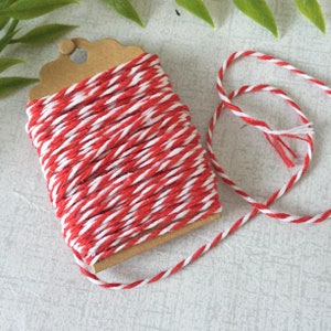 May include: Red and white baker's twine on a cardboard spool. The twine is striped with red and white.
