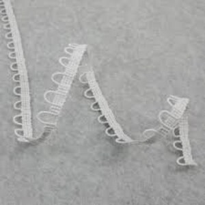 May include: White elastic trim with a scalloped edge and small loops. This trim is perfect for adding a decorative touch to clothing, crafts, and home decor projects.