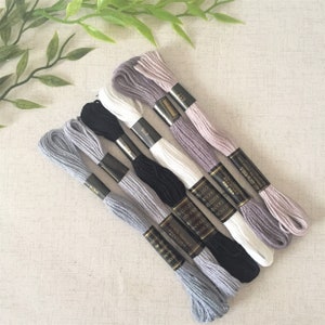 May include: Six spools of embroidery floss in various shades of grey, white, and black. The spools are labelled with the brand name "Bradford" and the text "Chess Strand Cotton Embroidery Floss".