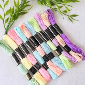 May include: A set of ten embroidery floss spools in various pastel colours, including pink, yellow, green, and blue. The spools are labelled with the brand name "Chess" and the number of the colour.
