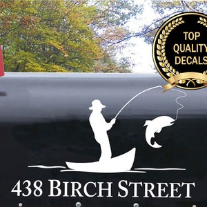 May include: White vinyl decal of a person fishing from a boat with a fish on the line. The decal is on a black mailbox with the address "438 Birch Street" printed below. A gold seal with the text "Top Quality Decals" is in the upper right corner.