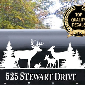 May include: White vinyl decal of a deer family with two fawns, a buck, and a doe, standing in a forest with pine trees. The decal is placed on a black mailbox with the address "525 Stewart Drive" printed below. The decal is a silhouette with a white outline.