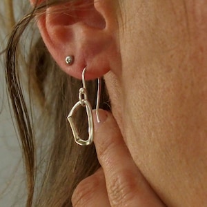 Peut inclure: Boucles d'oreilles pendantes en argent de forme rectangulaire. Les boucles d'oreilles sont en métal texturé et ont un design simple.