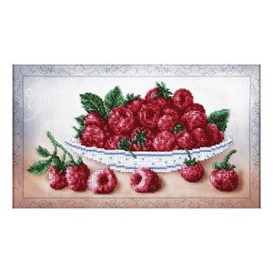 May include: A white bowl filled with red raspberries, with a few raspberries scattered on a brown surface. The bowl has a blue and white pattern.