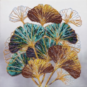 Könnte beinhalten: Nahaufnahme eines Perlenkunstwerks, das eine Ansammlung von Ginkgoblättern in Braun-, Grün- und Weißtönen darstellt. Die Blätter sind fächerförmig angeordnet und bilden ein optisch ansprechendes und komplexes Design.