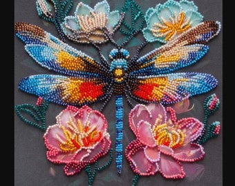 May include: A beaded dragonfly with blue, yellow, and red wings is surrounded by pink and blue flowers. The dragonfly and flowers are beaded on a dark gray canvas.