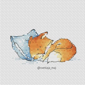 May include: A cross-stitch pattern of a fox sleeping on a blue pillow. The fox is orange and white and has its head tucked under its paw. The pillow has white dots on it. The text "@svetlaja_maj" is at the bottom of the image.