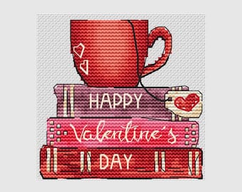 May include: Cross-stitch design featuring a red mug with heart accents atop a stack of books. The books display the words "HAPPY Valentine's DAY" in a decorative font, with a heart-shaped card. The color palette includes shades of red, pink, and purple.