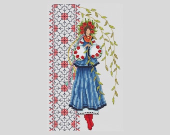 May include: A woman in a blue and white embroidered dress with a wreath of red flowers on her head. She is holding a bouquet of red flowers and standing in front of a white and red patterned background.