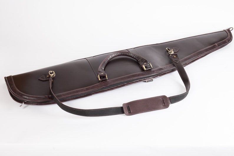 May include: A brown leather gun case with a zipper closure, a carrying handle, and an adjustable shoulder strap.