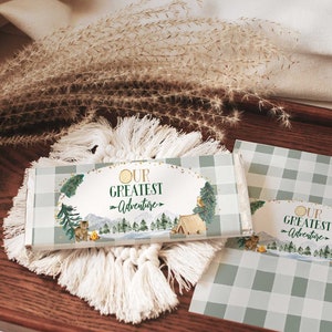 May include: A set of two green and white gingham patterned labels with gold text that reads "Our Greatest Adventure". The labels feature a woodland scene with a campfire, trees, and a tent.