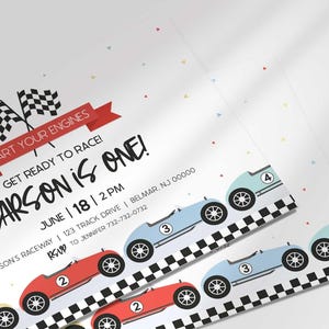 Close-up angled shot of the printed invitation with scattered confetti, highlighting the checkered flags and row of race cars.