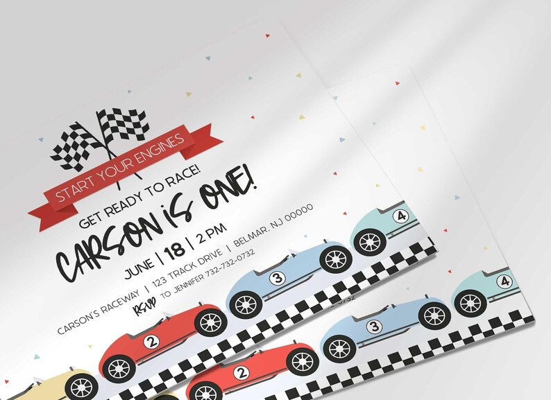 Close-up angled shot of the printed invitation with scattered confetti, highlighting the checkered flags and row of race cars.