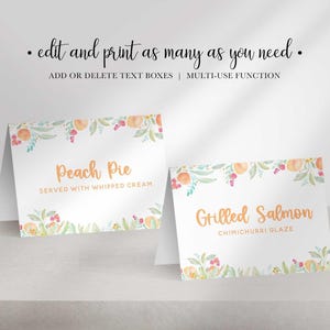 Two folded white paper place cards with watercolor peach borders display the text Peach Pie and Grilled Salmon in orange font.