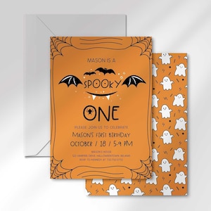 Mason's Halloween-themed 'Spooky One' first birthday invitation layered in front of its matching envelope and a second card showing an orange back design with a white ghost pattern.