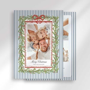 Two stacked Christmas greeting cards angled on a surface, displaying the front with a family photo and blue and white stripes.