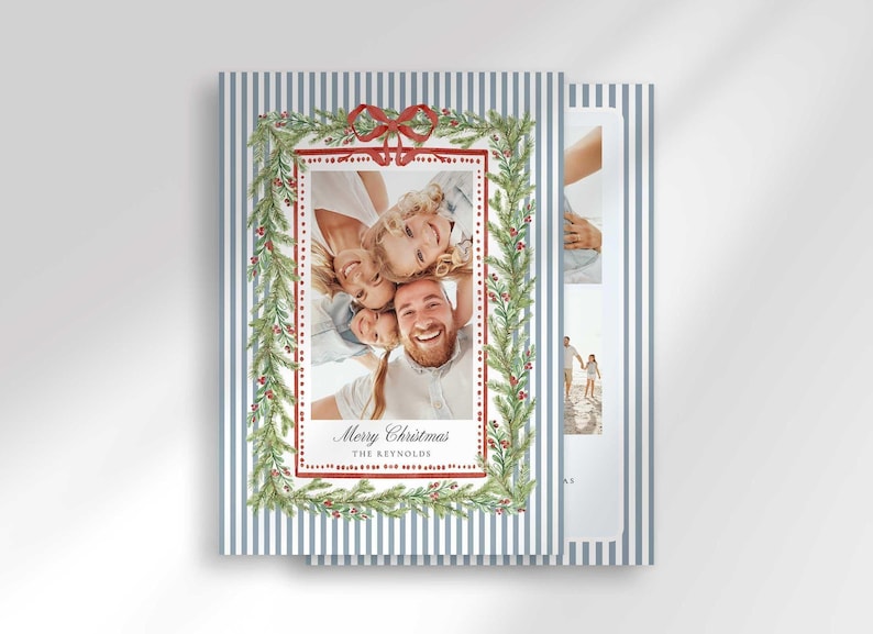 Two stacked Christmas greeting cards angled on a surface, displaying the front with a family photo and blue and white stripes.