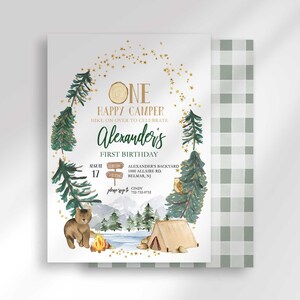 Alexander's camping-themed first birthday invitation with a second card showing a sage green plaid back design peeking out behind it.