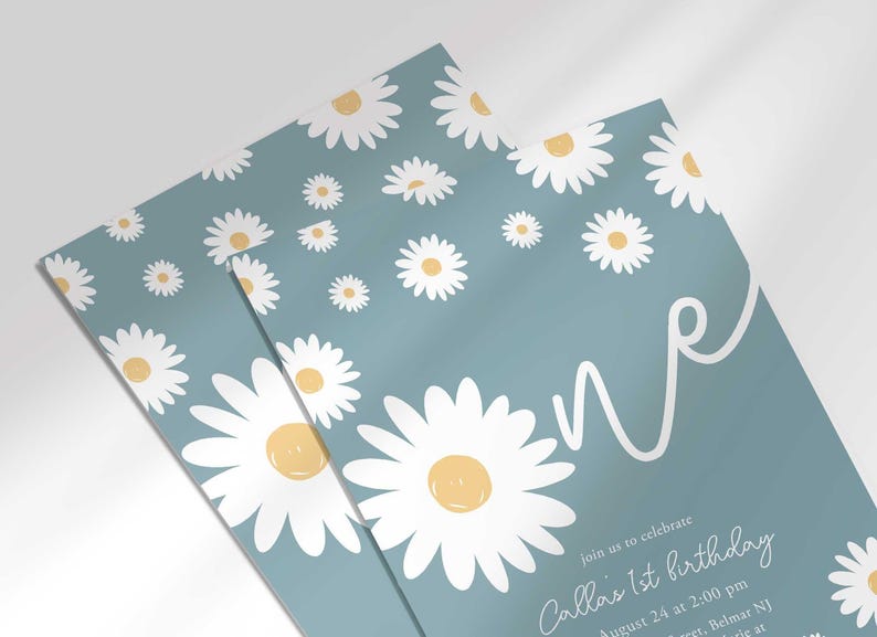 Close-up angled shot of the 'ONE' daisy-themed invitation for Callie's 1st birthday in slate blue, showing the print quality and daisy pattern detail.
