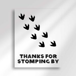 A vertical sign featuring black dinosaur footprints walking diagonally and text that reads Thanks For Stomping By.