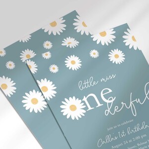 Close-up angled stack of two prints of the 'Little Miss ONEderful' daisy-themed invitation for Callie's 1st birthday, showing the print quality and daisy pattern detail.