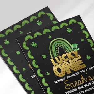 Angled stack of two printed "Lucky One" invitation cards, both showing the same black St. Patrick's Day design for Sarah's first birthday.