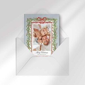 A Christmas greeting card placed inside a white envelope on a neutral background.