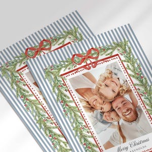 A close-up view of two overlapping Christmas greeting cards showing the detailed pine garland, red bow, and family portrait.