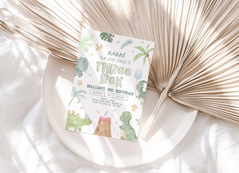 Lifestyle photo of William's dinosaur-themed birthday invitation propped on a white plate with a dried palm frond, styled on a linen tablecloth.