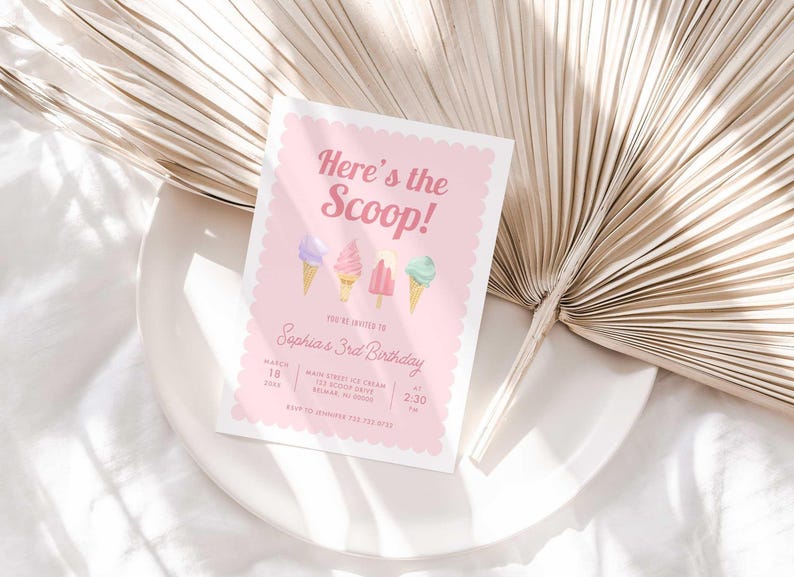 Styled lifestyle photo of the printed invitation propped on a white plate with a dried palm frond, showing the "Here's the Scoop!" ice cream design.