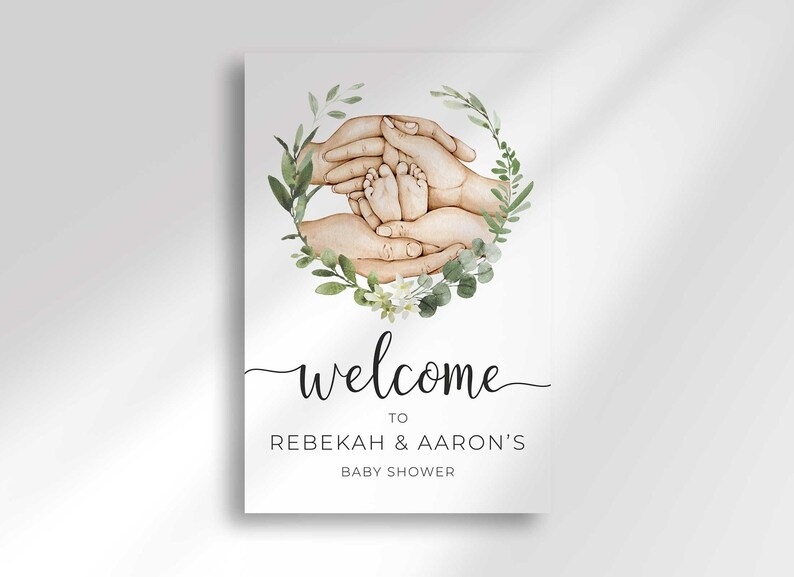 Close-up flat view of the printed Welcome To Rebekah & Aaron's Baby Shower sign with the watercolor hands and greenery wreath.