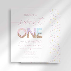 Sweet One first birthday invitation card layered over a colorful confetti sprinkle patterned envelope liner, with "Olivia is a Sweet ONE, join us to celebrate Olivia's first birthday" text, ONE in a pink and tan textured font, and party details including date, time, and location.