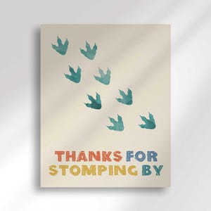'Thanks for Stomping By' favor sign with a trail of teal dinosaur footprint illustrations.