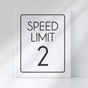 A white framed vertical sign reads SPEED LIMIT 2 in bold black letters against a white background.