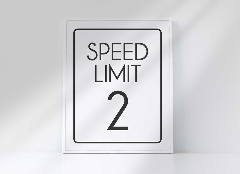 A white framed vertical sign reads SPEED LIMIT 2 in bold black letters against a white background.