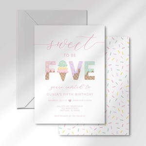 The invitation's front design shown angled and stacked in front of a matching pastel sprinkle-pattern back and a gray envelope.