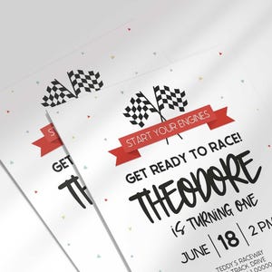 Close-up angled shot of two overlapping printed invitations with scattered confetti, highlighting the checkered flags.